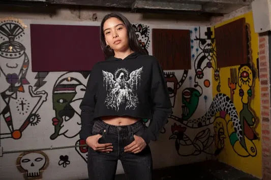 Female model wearing black 320 GSM cotton cropped hoodie with detailed white angel graphic for dark streetwear look.